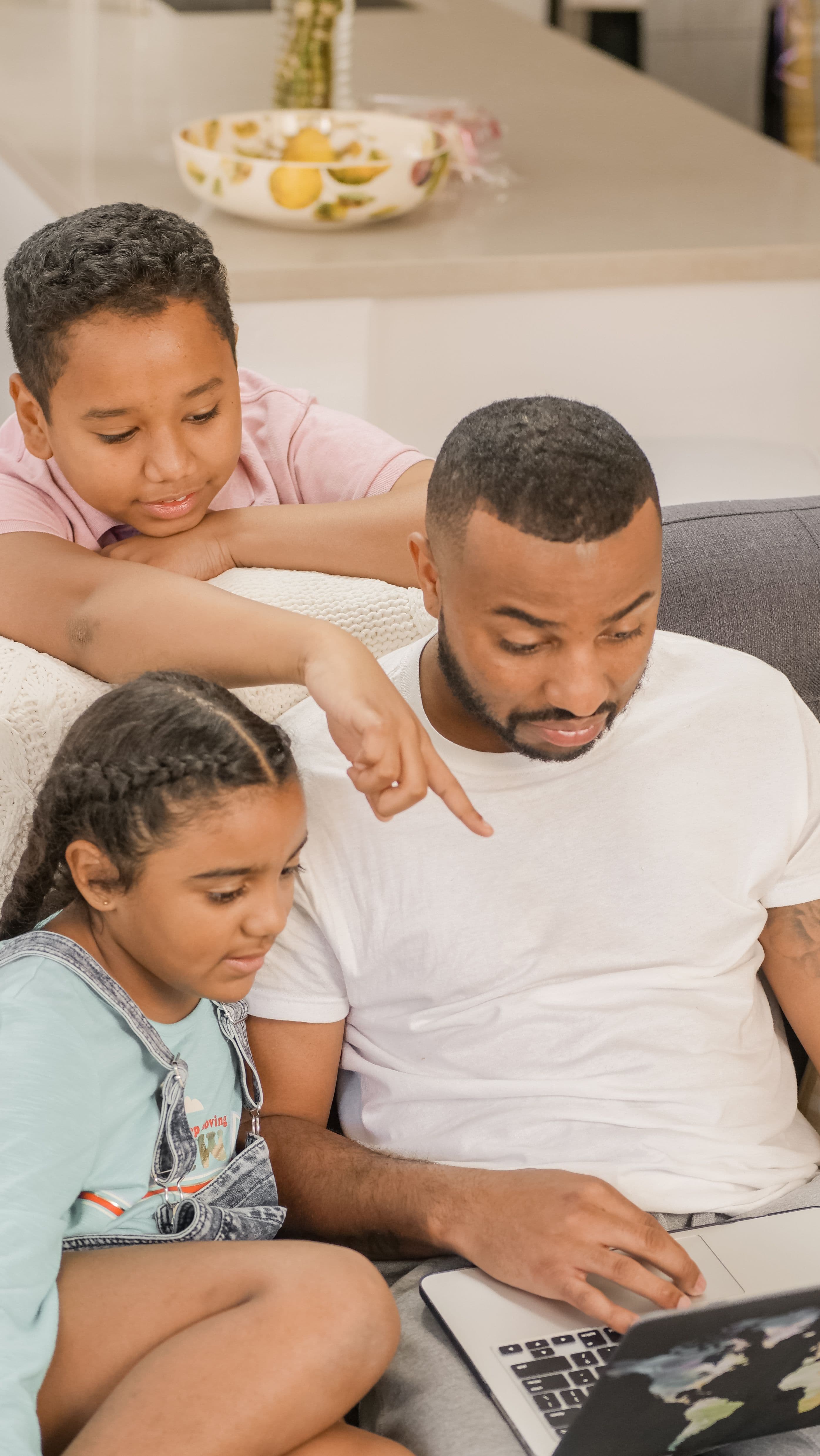A father and his children pointing at a laptop screen, discovering open school spots together